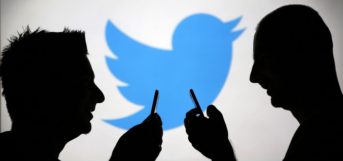 Men are silhouetted against a video screen with an Twitter logo as he poses with an Samsung S4 smartphone in this photo illustration taken in the central Bosnian town of Zenica, August 14, 2013. REUTERS/Dado Ruvic (BOSNIA AND HERZEGOVINA - Tags: BUSINESS TELECOMS)
